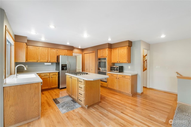 kitchen featuring a kitchen island, sink, stainless steel appliances, and light hardwood / wood-style flooring