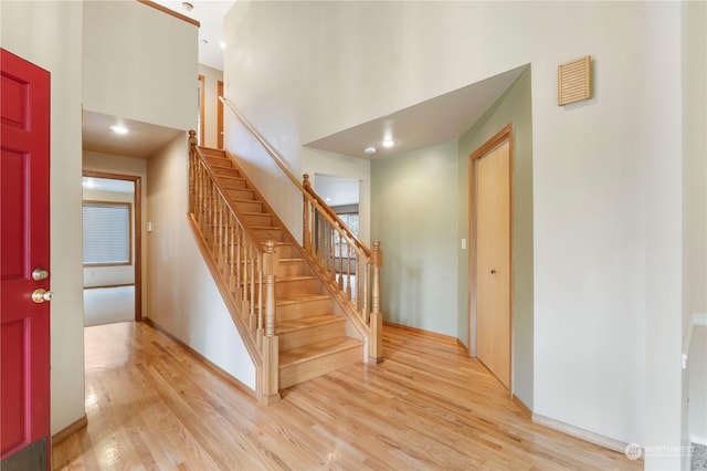 staircase with a towering ceiling and hardwood / wood-style flooring