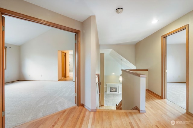 hallway with lofted ceiling and light wood-type flooring