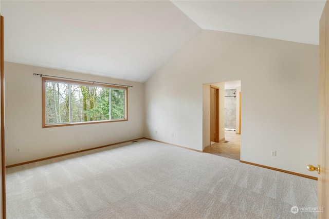 empty room with light colored carpet and high vaulted ceiling