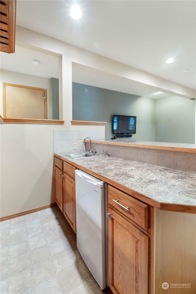 kitchen featuring dishwashing machine, kitchen peninsula, and sink