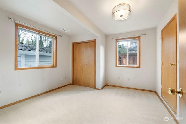 unfurnished bedroom with a closet, light colored carpet, and multiple windows