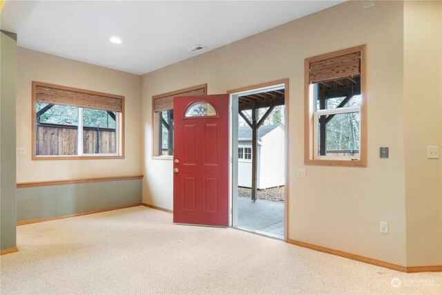 foyer entrance with plenty of natural light and light colored carpet