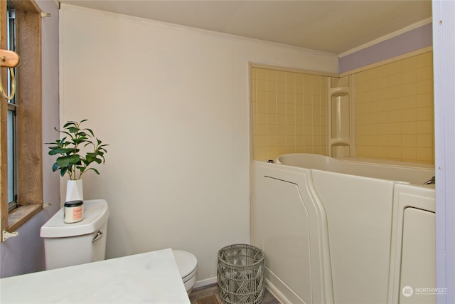 bathroom featuring a washtub, ornamental molding, and toilet