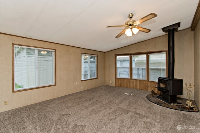 unfurnished living room featuring carpet floors, a wood stove, ceiling fan, and lofted ceiling