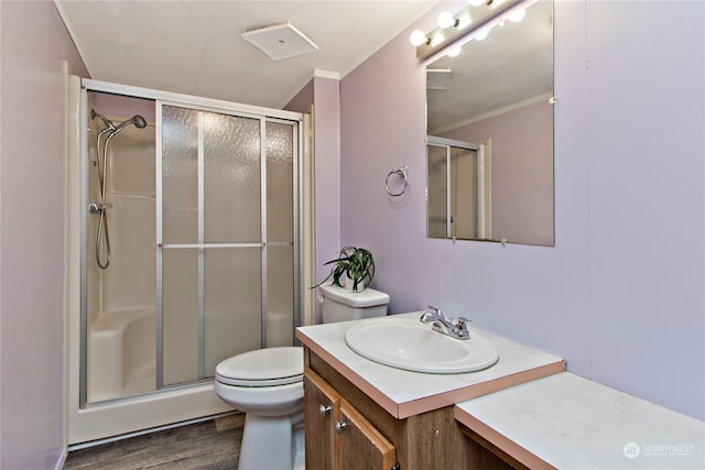 bathroom with wood-type flooring, an enclosed shower, toilet, vanity, and ornamental molding