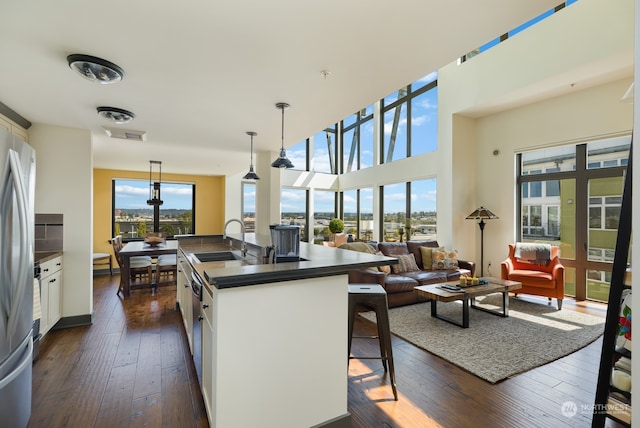 kitchen with white cabinets, decorative light fixtures, a kitchen island with sink, and sink