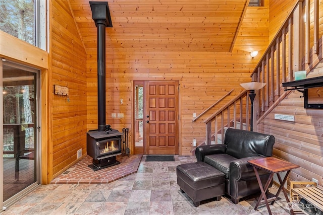 sitting room featuring plenty of natural light, wood walls, and high vaulted ceiling