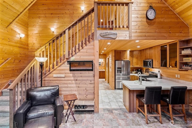 kitchen featuring wooden walls, kitchen peninsula, wood ceiling, and appliances with stainless steel finishes