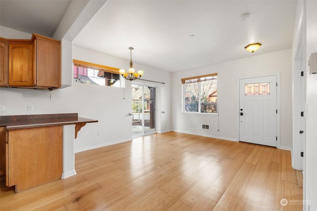 2606 Peach Ct Unit B, Port Angeles, WA 98363 - kitchen with a chandelier, light wood-style floors, dark countertops, brown cabinetry, and plenty of natural light