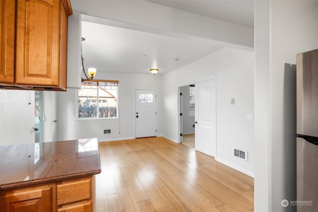 2606 Peach Ct Unit B, Port Angeles, WA 98363 - kitchen featuring light wood finished floors, freestanding refrigerator, baseboards, brown cabinets, and dark stone counters