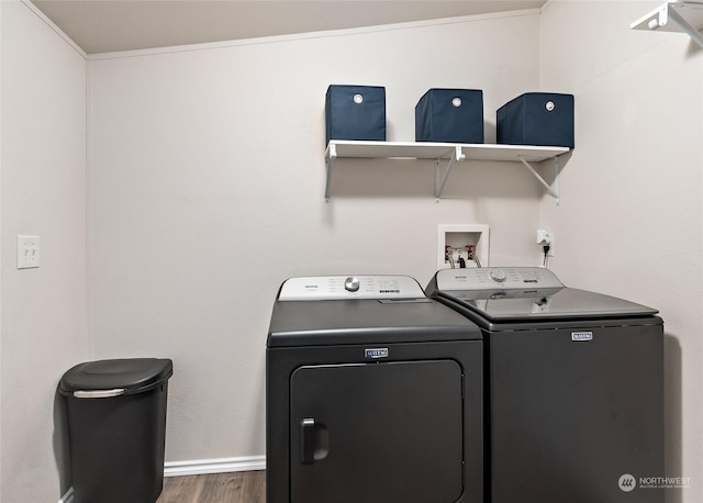 laundry room with crown molding, dark wood-type flooring, and washing machine and clothes dryer