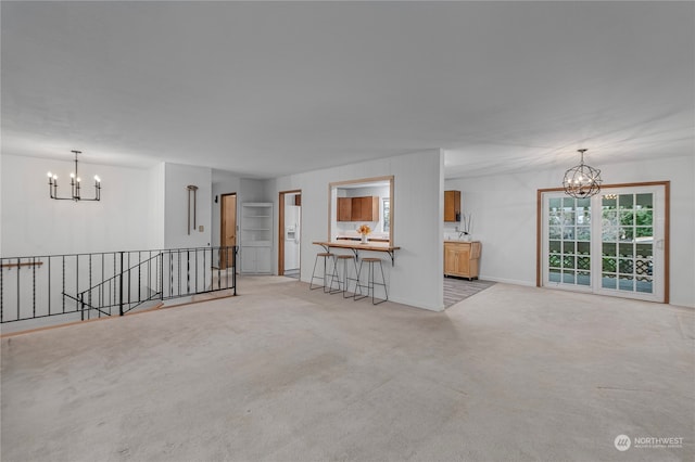 unfurnished living room featuring light carpet and an inviting chandelier