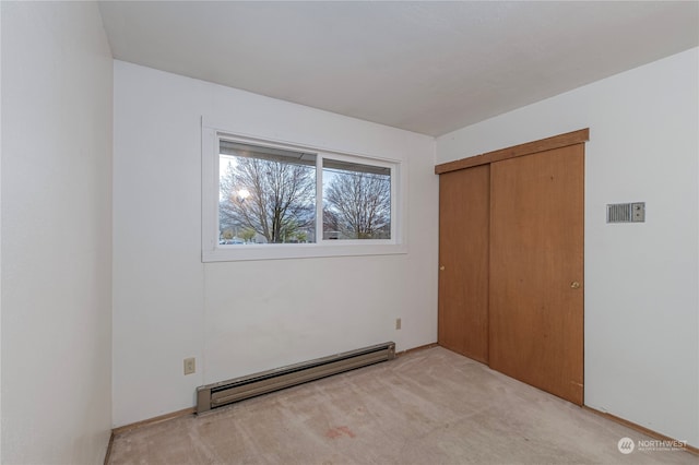 unfurnished bedroom featuring carpet floors, baseboard heating, and a closet