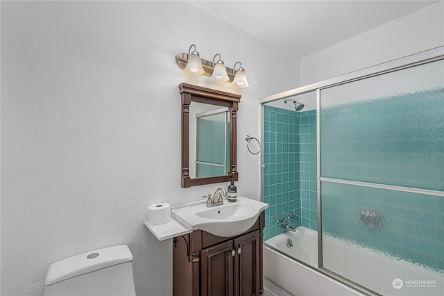 bathroom featuring toilet, bath / shower combo with glass door, and vanity