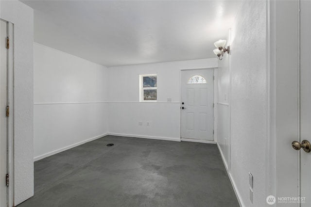 entrance foyer with baseboards and concrete flooring