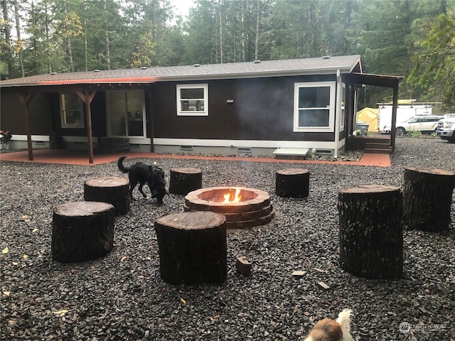 back of property with a fire pit and a patio