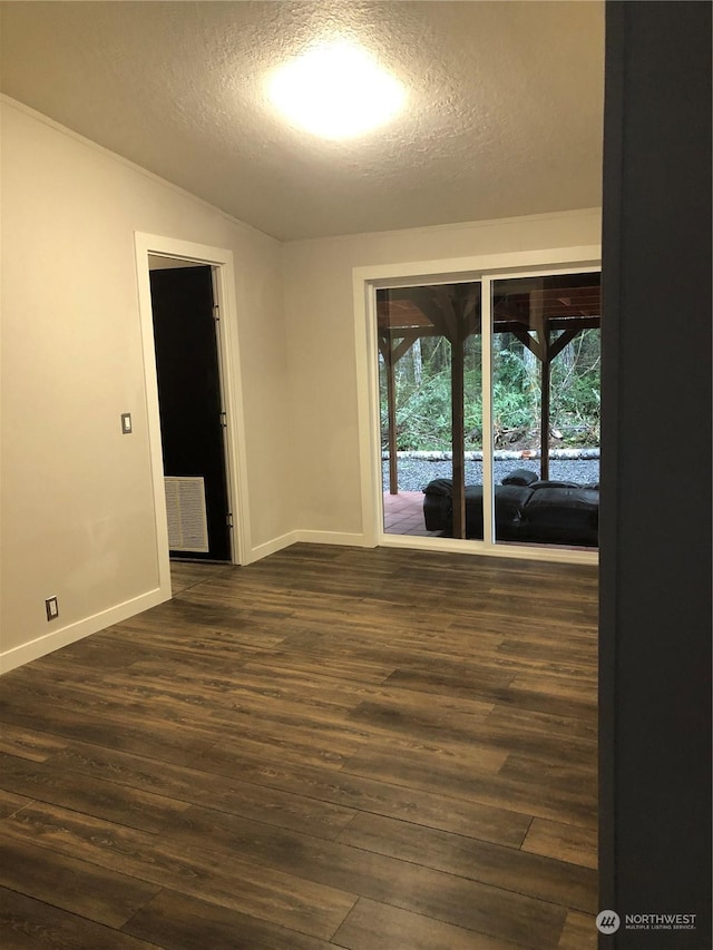 unfurnished room with dark hardwood / wood-style floors, a textured ceiling, and vaulted ceiling