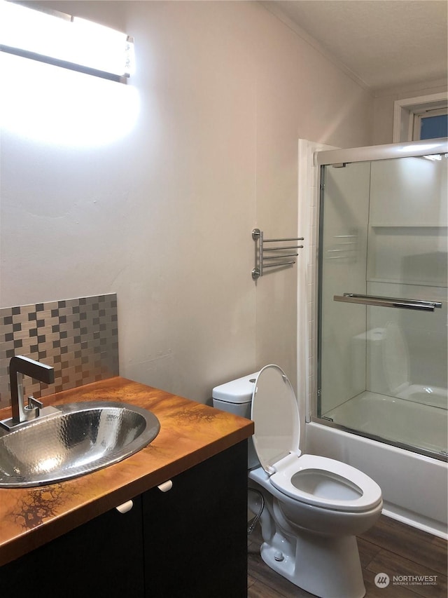 full bathroom with shower / bath combination with glass door, hardwood / wood-style floors, vanity, and toilet