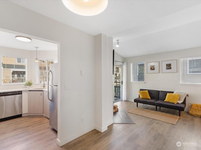 living room with sink, vaulted ceiling, and light wood-type flooring