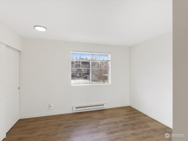 spare room with dark hardwood / wood-style floors and a baseboard heating unit