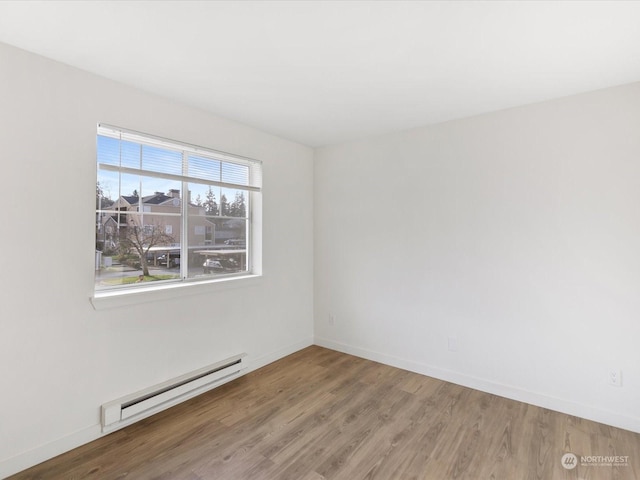 empty room with hardwood / wood-style flooring and a baseboard heating unit