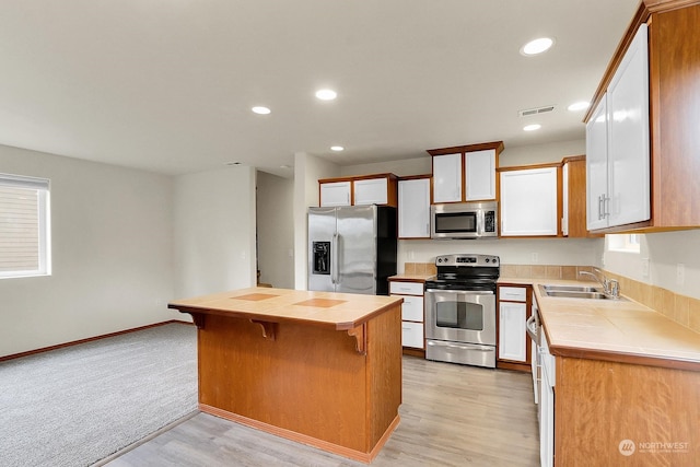 kitchen featuring a kitchen breakfast bar, sink, light wood-type flooring, a kitchen island, and stainless steel appliances