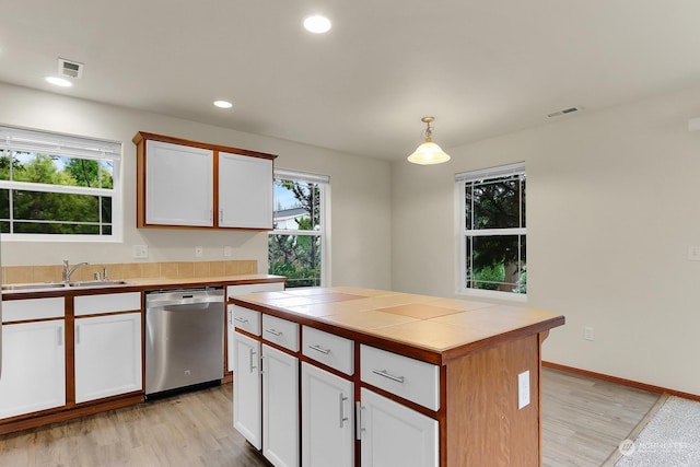 kitchen featuring stainless steel dishwasher, pendant lighting, light hardwood / wood-style flooring, white cabinets, and tile counters