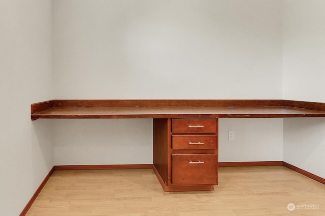 unfurnished office with light wood-type flooring and built in desk