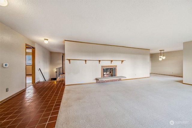 unfurnished living room featuring a fireplace, dark tile patterned flooring, and a textured ceiling