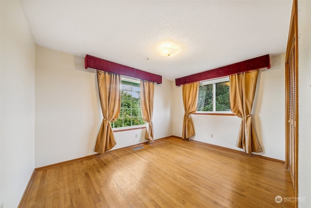 unfurnished room featuring hardwood / wood-style floors, a wealth of natural light, and a textured ceiling