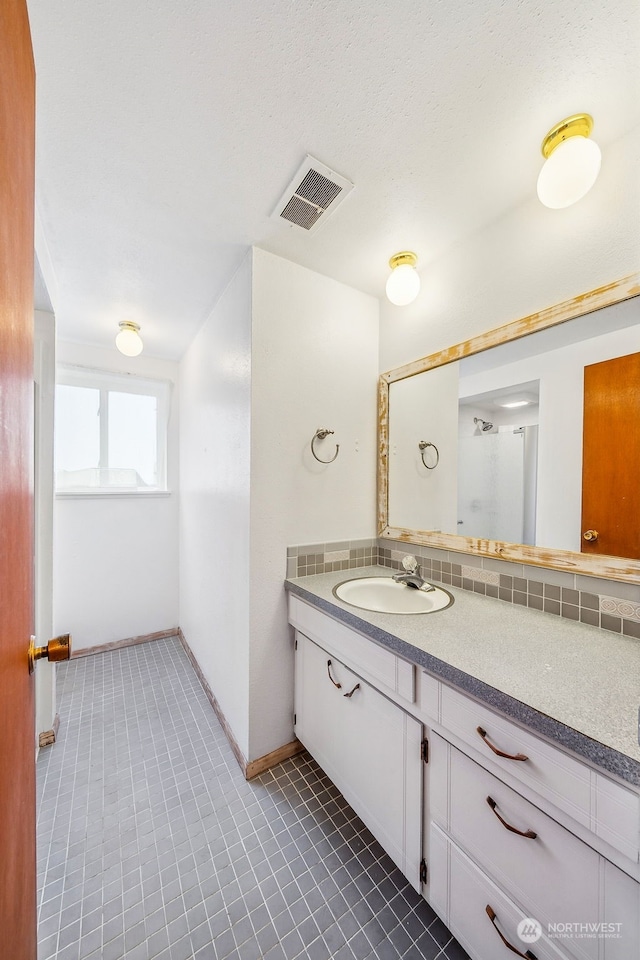 bathroom featuring tasteful backsplash, vanity, and tile patterned flooring