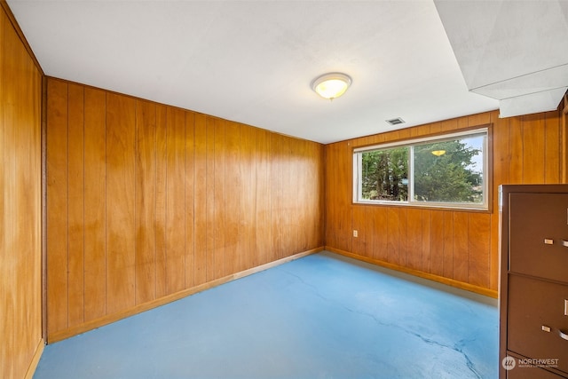 unfurnished room featuring wooden walls