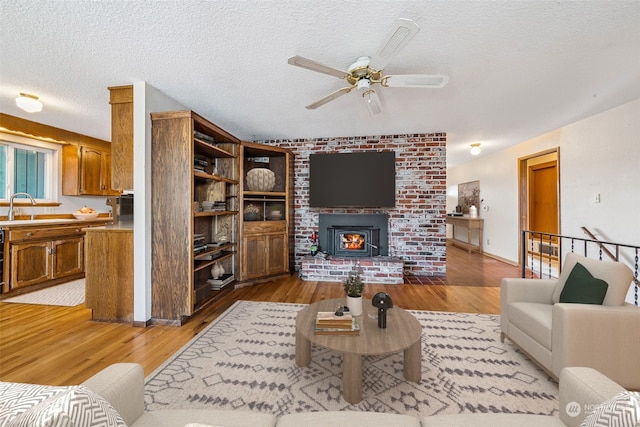 living room featuring sink, hardwood / wood-style flooring, a textured ceiling, and ceiling fan