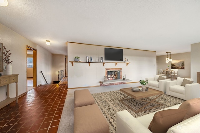 living room with a brick fireplace, a textured ceiling, and dark tile patterned floors