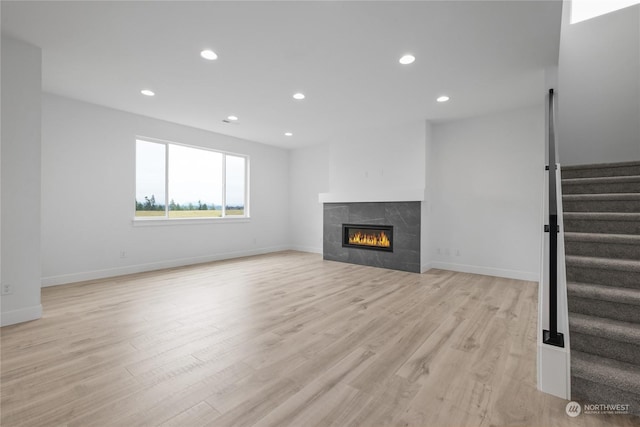 unfurnished living room with a tile fireplace and light hardwood / wood-style flooring