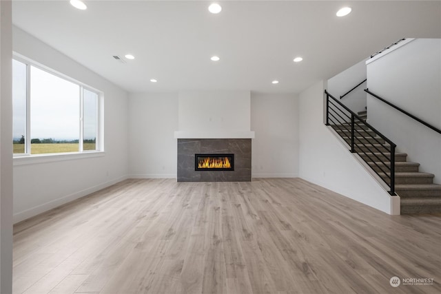 unfurnished living room featuring light wood-type flooring and a tiled fireplace