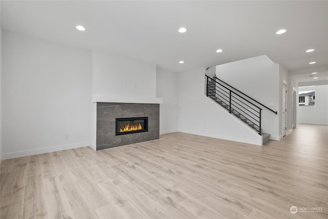 unfurnished living room featuring light hardwood / wood-style flooring and a tiled fireplace