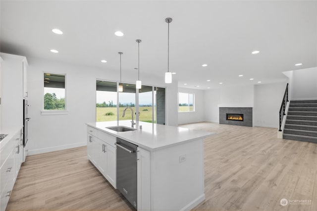 kitchen featuring appliances with stainless steel finishes, a kitchen island with sink, sink, pendant lighting, and light hardwood / wood-style flooring