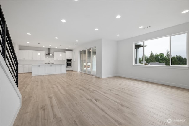 unfurnished living room featuring light wood-type flooring and sink