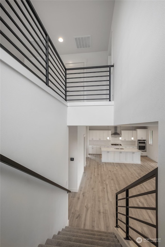 stairway featuring hardwood / wood-style floors, a towering ceiling, and sink