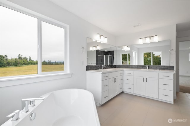 bathroom with a washtub, decorative backsplash, and vanity