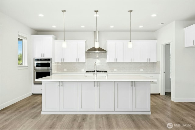 6202 229th Ave E, Buckley, WA 98321 - kitchen with stainless steel double oven, wall chimney range hood, light wood finished floors, white cabinetry, and recessed lighting