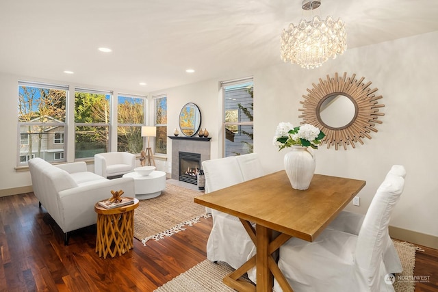 dining area featuring a fireplace, wood-type flooring, and a chandelier