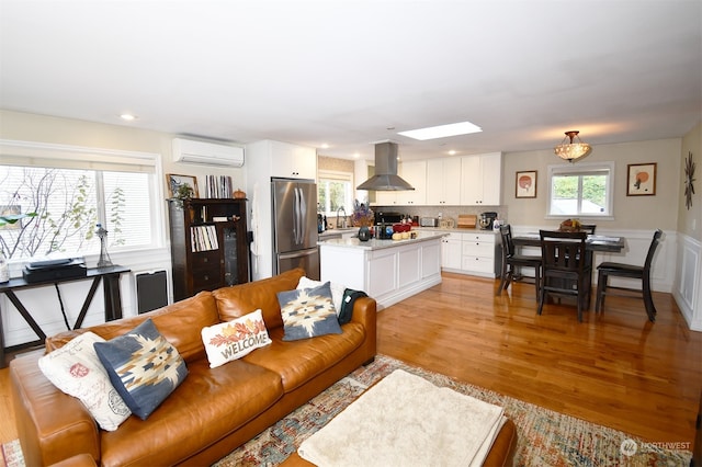 living room featuring sink, light hardwood / wood-style floors, a wealth of natural light, and an AC wall unit