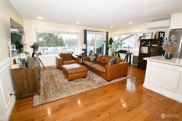 living room featuring a wall mounted air conditioner and light hardwood / wood-style flooring