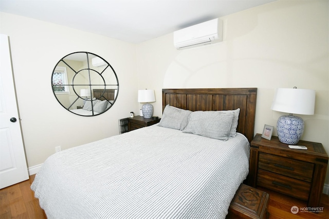 bedroom with hardwood / wood-style floors and a wall unit AC