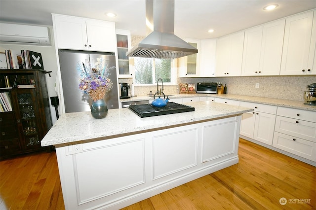 kitchen with white cabinets, stainless steel appliances, island exhaust hood, and a center island