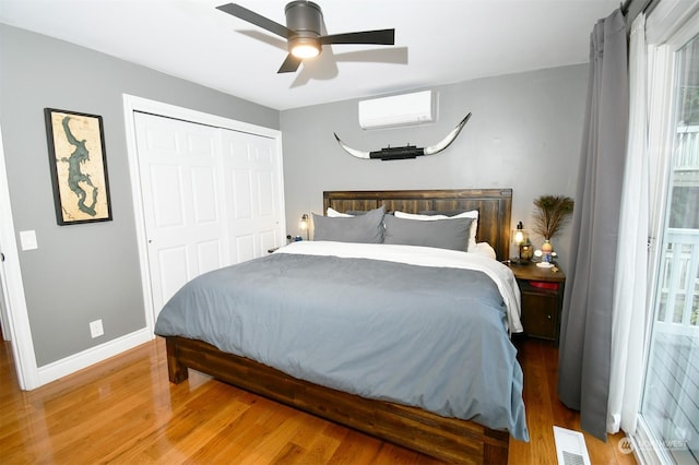 bedroom featuring ceiling fan, a wall mounted AC, a closet, and hardwood / wood-style flooring