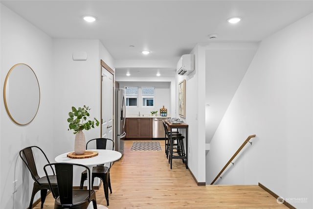 dining area featuring light wood-type flooring and a wall unit AC